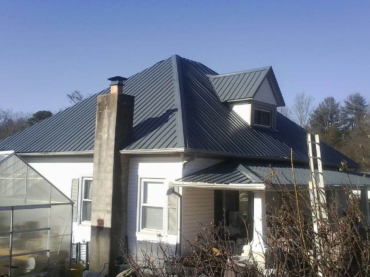 Dark blue standing seam metal roof on a white farmhouse with dormer — Slate & Tile Roof Repair by Roofing Brothers in Homer Glen