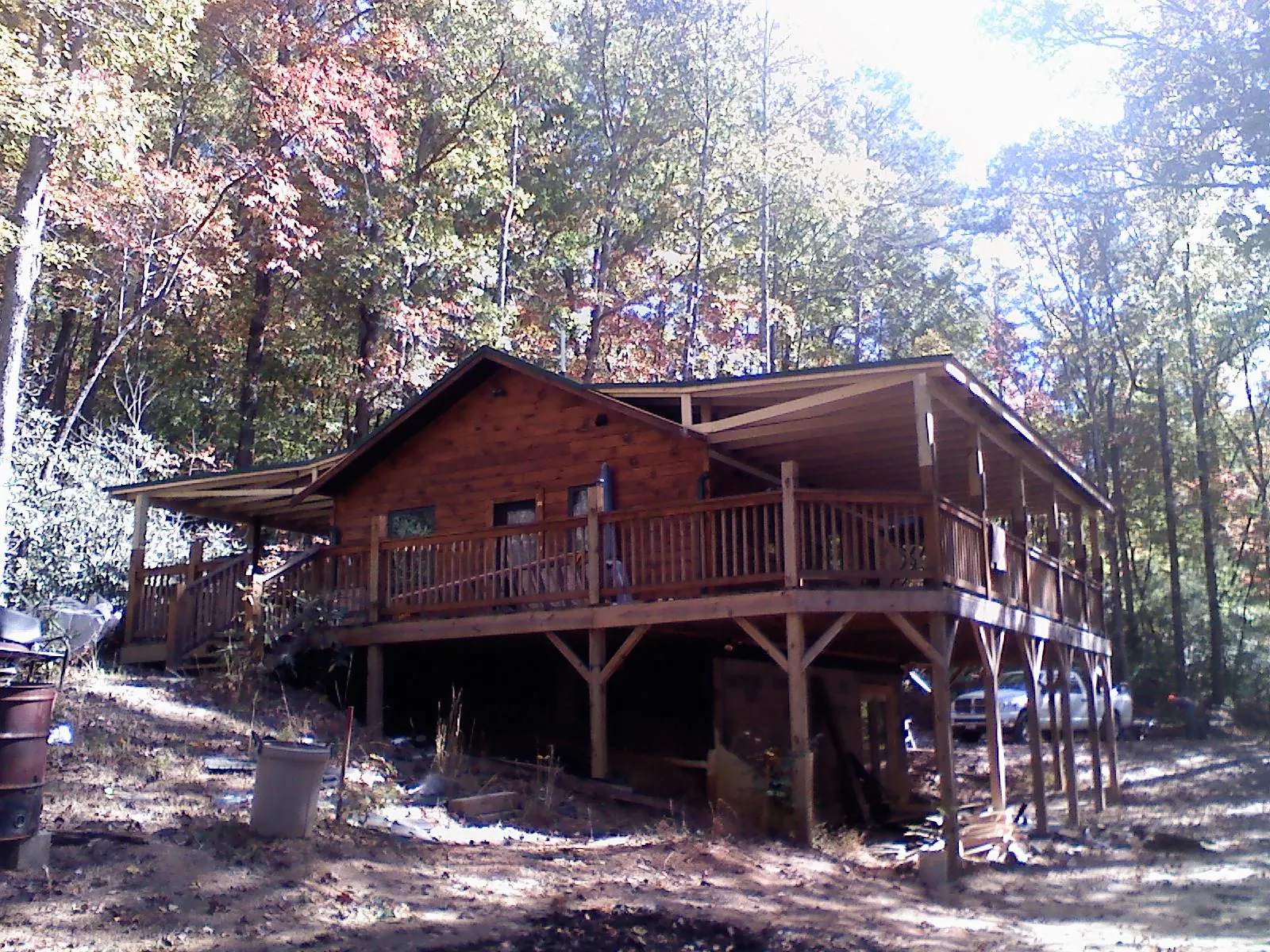 Log cabin with a wraparound porch and metal roof in the fall in Homer Glen