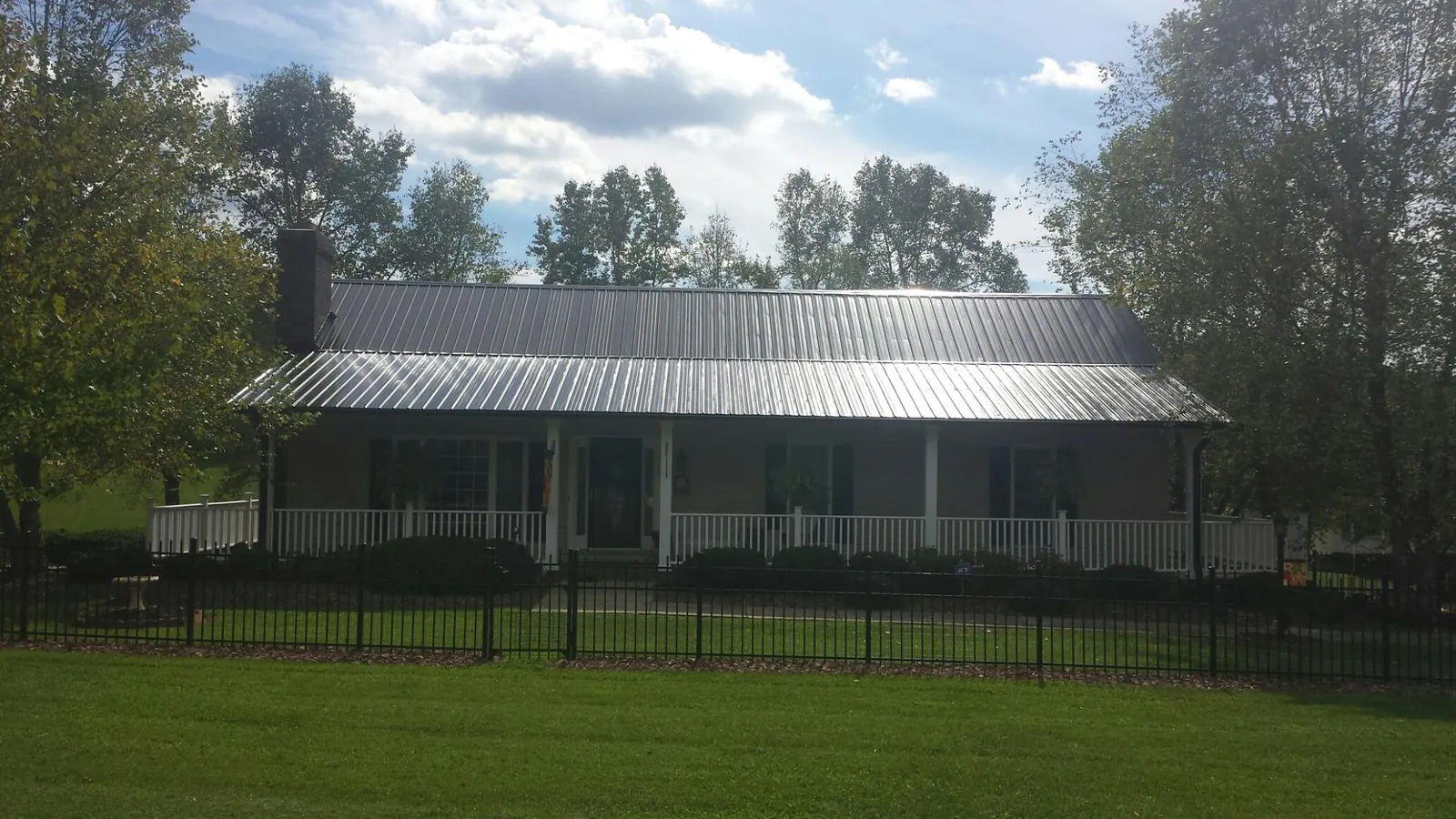 Gray metal roof on a brick ranch with a full width front porch — Gutter Guard Installation work by our crew in Homer Glen
