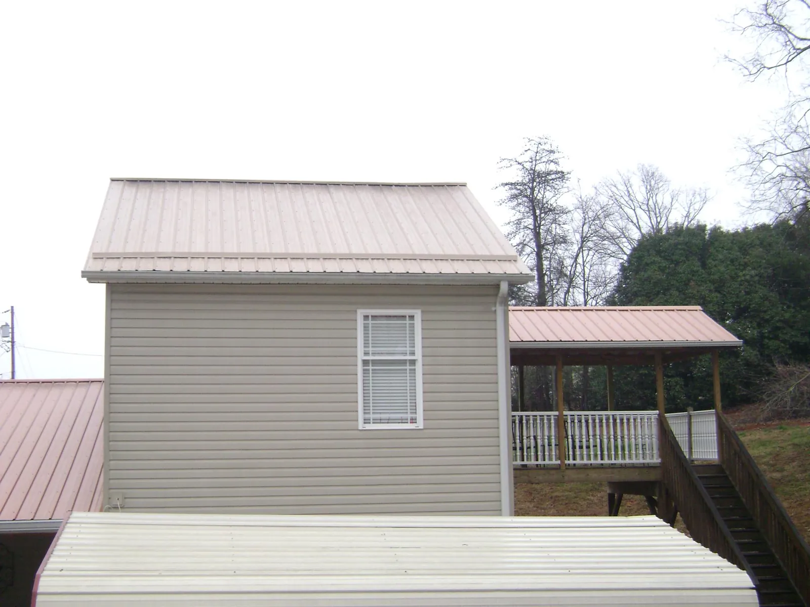 Tan metal roofs on a two story addition and attached porch, from a Roof Replacement job in Homer Glen
