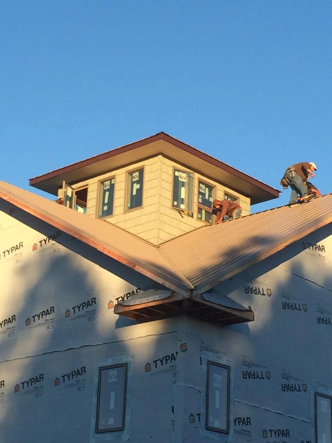 Roofers working around a rooftop cupola on a new metal roof at sunset — Roof Waterproofing in Homer Glen by Roofing Brothers